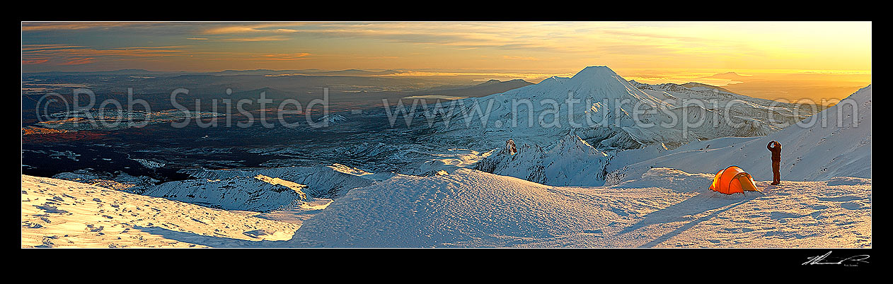 Image of Mount Ngauruhoe sunrise (2287m) from alpine tent camp near summit of Mt Ruapehu. Mt Tongariro (1967m) and Lake Taupo behind. Heavy winter snow. Panorama, Tongariro National Park, Ruapehu District, Manawatu-Wanganui Region, New Zealand (NZ) stock photo image