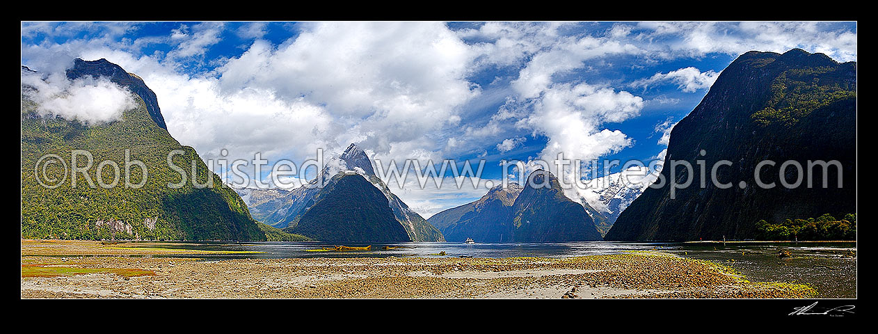 Image of Milford Sound Panorama, Fiordland National Park. Small boat tour leaving Freshwater Basin. Mitre Peak left (1683m), Stirling Falls centre, The Lion and Mt Pembroke (2015m in snow), Milford Sound, Fiordland National Park, Southland District, Southland Region, New Zealand (NZ) stock photo image