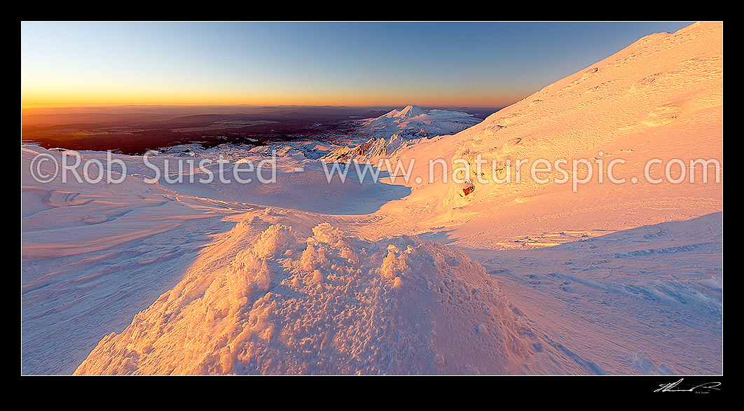 Image of Mount Ngauruhoe sunset (2287m) from near summit of Mt Ruapehu. Whakapapa and Pinnacle Ridge in foreground. Heavy winter snow with wind crusted surface. Panorama, Tongariro National Park, Ruapehu District, Manawatu-Wanganui Region, New Zealand (NZ) stock photo image