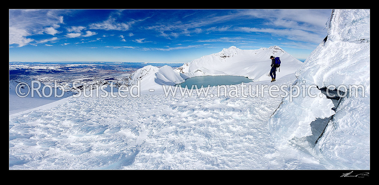 Image of Tramper at Dome Shelter (ice encrusted) near summit and Crater Lake of Mount Ruapehu (2797m Tahurangi Peak centre right). Whangaehu Valley and Rangipo Desert left. Ice textures in panorama, Tongariro National Park, Ruapehu District, Manawatu-Wanganui Region, New Zealand (NZ) stock photo image