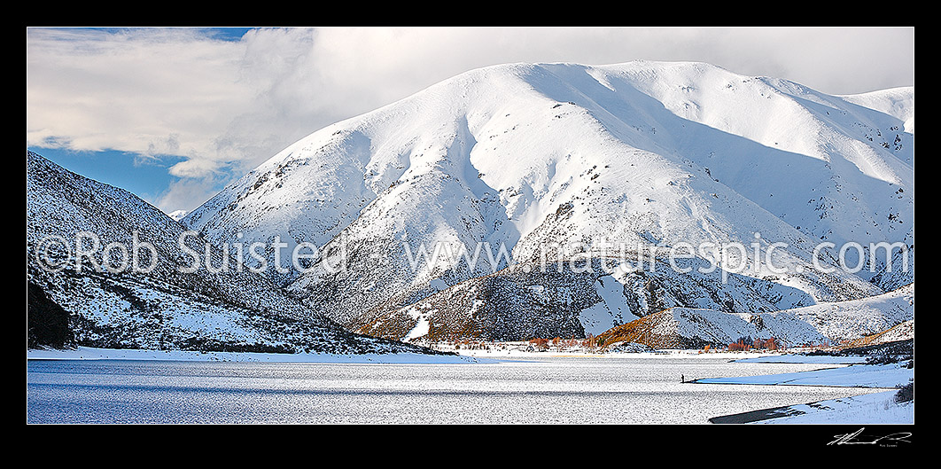 Image of Lake Lyndon with Torlesse Range beyond in heavy winter snowfall. Trout flyfisherman fishing on shoreline. Panorama, Porters Pass, Selwyn District, Canterbury Region, New Zealand (NZ) stock photo image