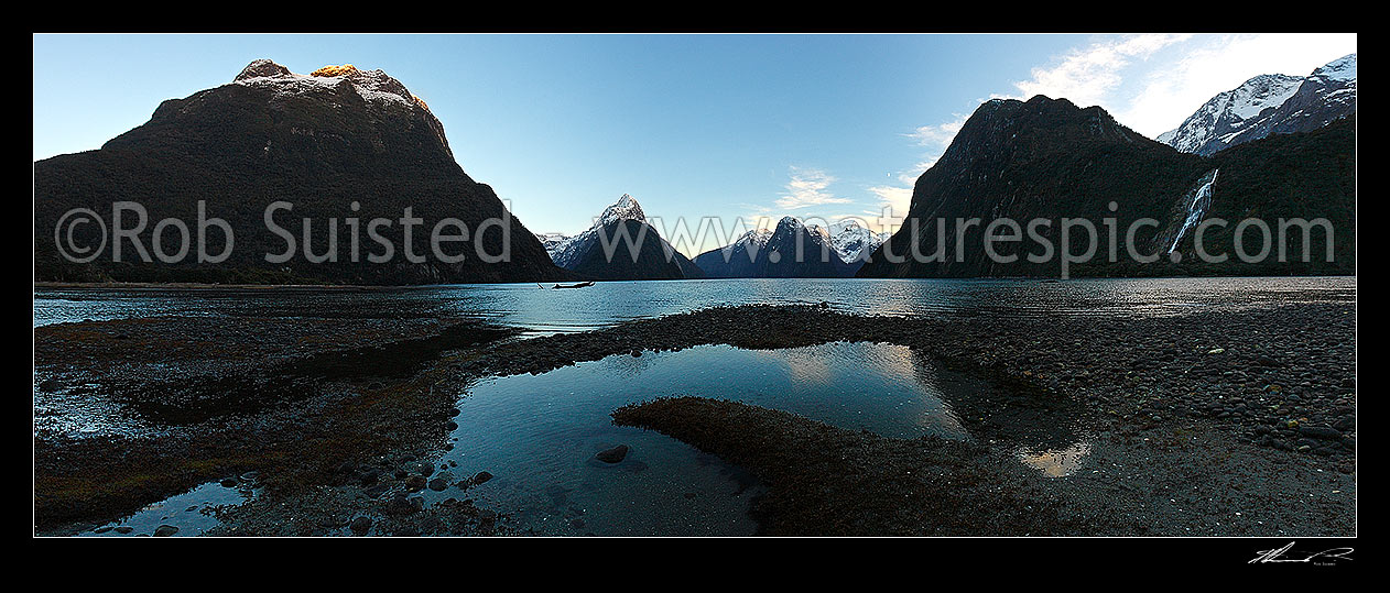 Image of Mitre Peak in Milford Sound Fiordland. Mitre Peak centre left (1683m), The Lion (1302m) and Mt Pembroke (2015m) centre right, Bowen Falls right. Panorama at dawn, Milford Sound, Fiordland National Park, Southland District, Southland Region, New Zealand (NZ) stock photo image