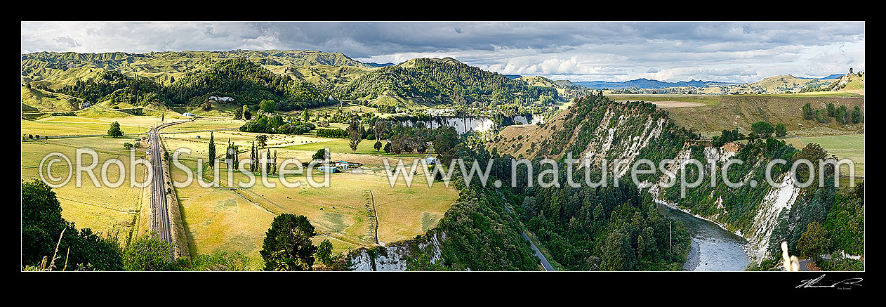 Image of Mangaweka township visible beyond farmland and white siltstone cliffs above the Rangitikei River. North Island main trunk line left. Panorama, Mangaweka, Rangitikei District, Manawatu-Wanganui Region, New Zealand (NZ) stock photo image