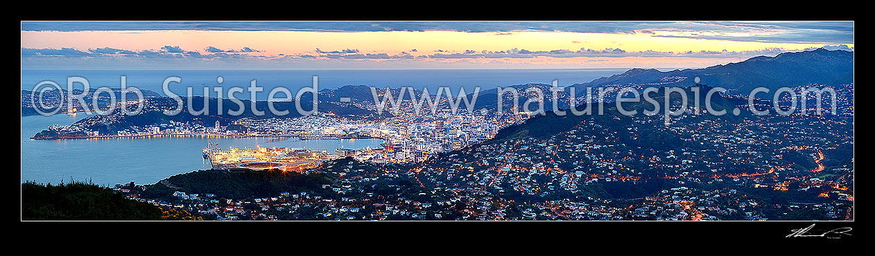 Image of Wellington Harbour, CBD and City at twilight with lights glowing. Panorama from Evans Bay / airport to Wadestown / Karori (right), Cook Strait beyond, Wellington City, Wellington City District, Wellington Region, New Zealand (NZ) stock photo image