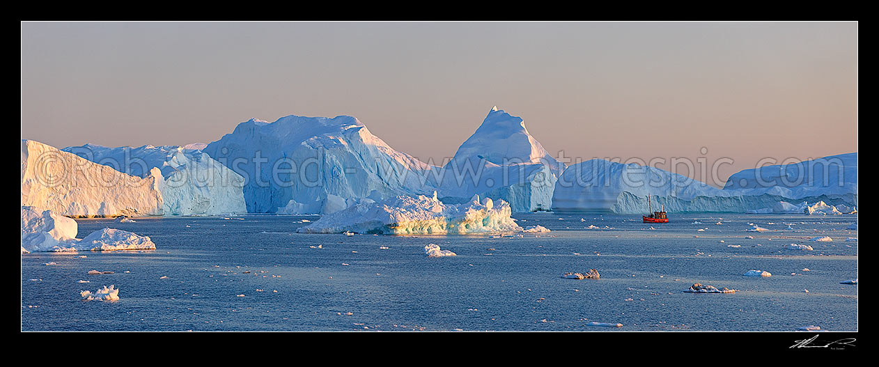 Image of Ilulissat Icefjord, giant icebergs at entrance to Ilulissat Kangerlua after leaving the Jakobshavn Isbr glacier. Sunset and fishing boat panorama, Ilulissat, Greenland stock photo image