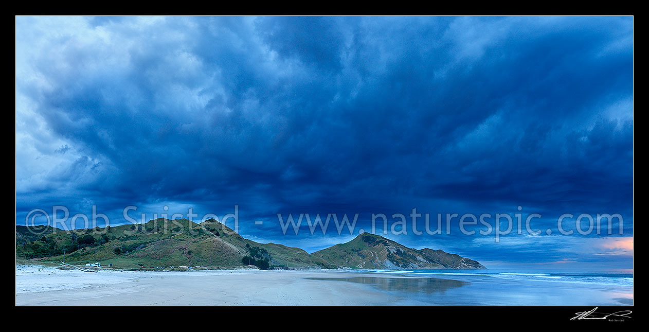 Image of Kaiaua Bay Beach moody sunset panorama, as storm clouds gather, with Marau Point right, Tolaga Bay, Gisborne District, Gisborne Region, New Zealand (NZ) stock photo image