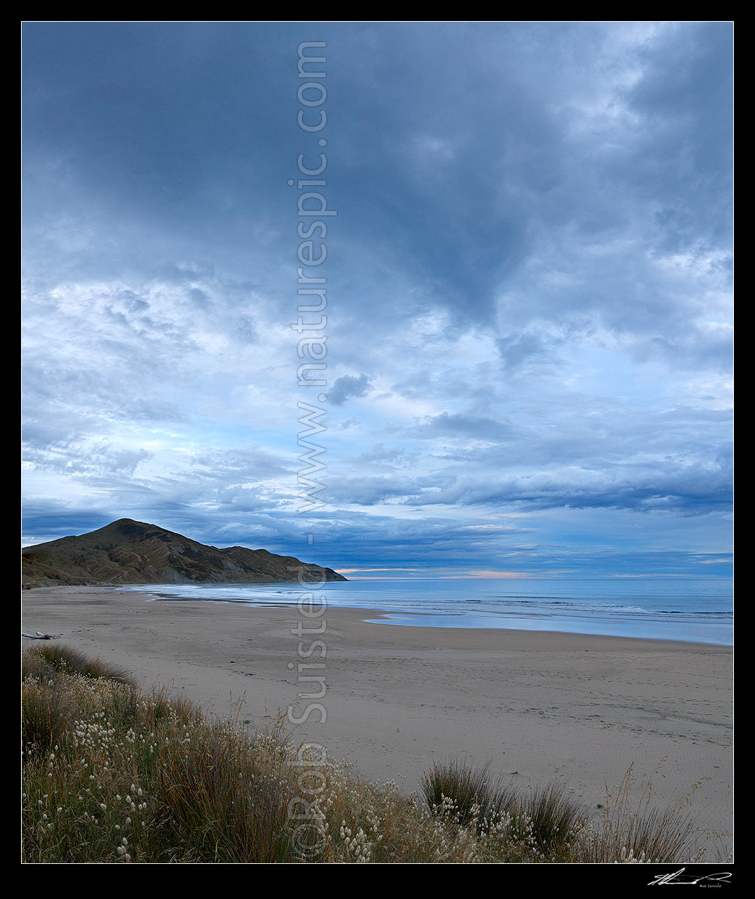 Image of Kaiaua Bay Beach moody twilight as storm clouds gather, with Marau Point centre. Square format, Tolaga Bay, Gisborne District, Gisborne Region, New Zealand (NZ) stock photo image