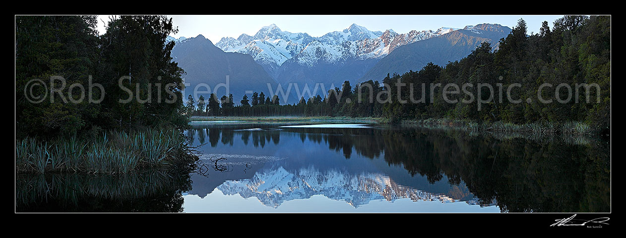 Image of Lake Matheson. Morning calm reflections on lake with Aoraki / Mount Cook (right;3754m) and Mount Tasman (left;3498m). Panorama. South Westland, Westland National Park, Westland District, West Coast Region, New Zealand (NZ) stock photo image