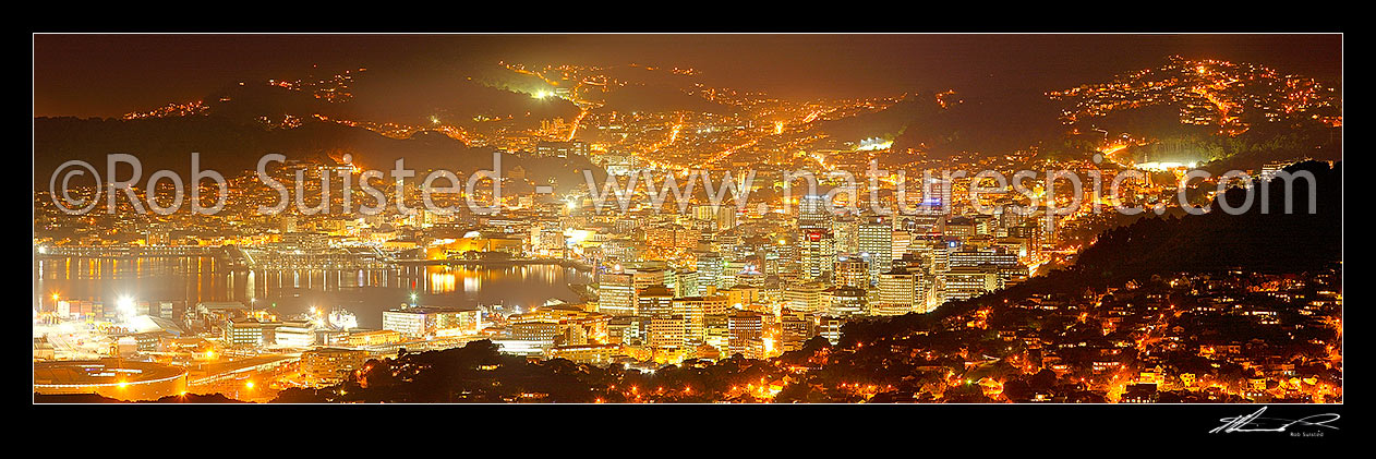 Image of Wellington City at night. Central business district (CBD), buildings, harbour and suburbs glowing with lights after dark. Panorama, Wellington, Wellington City District, Wellington Region, New Zealand (NZ) stock photo image