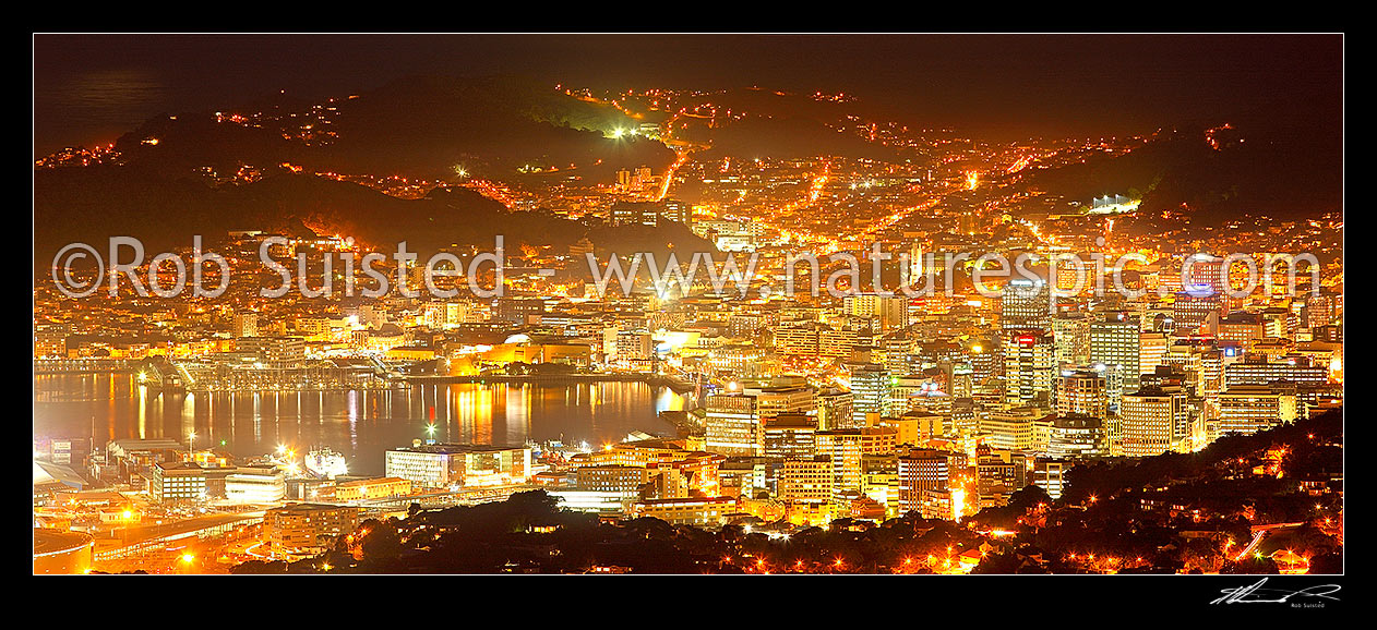 Image of Wellington City at night. Central business district (CBD), buildings, harbour and suburbs glowing with lights after dark. Panorama, Wellington, Wellington City District, Wellington Region, New Zealand (NZ) stock photo image