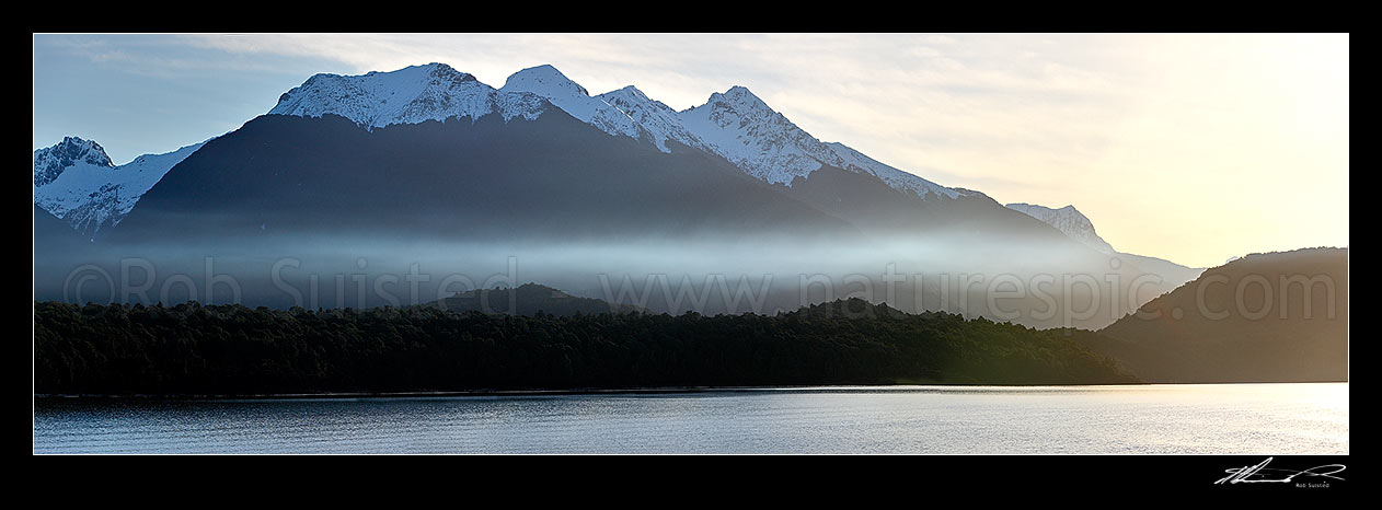 Image of Lake Manapouri at dusk, with snow capped Kepler Mountains behind, in winter. Panorama, Manapouri, Southland District, Southland Region, New Zealand (NZ) stock photo image