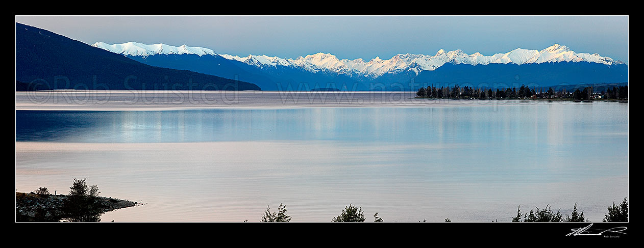 Image of Lake Te Anau panorama from the southern end. Te Anau township far right, snow capped Fiordland Mountains and National Park distant, Te Anau, Southland District, Southland Region, New Zealand (NZ) stock photo image