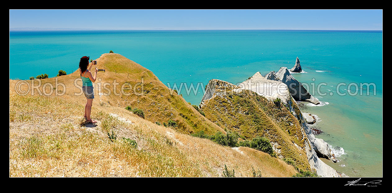 Image of Visitor to Cape Kidnappers, taking photos of the Saddle Gannet Colony and azure blue sea. Summer panorama, Cape Kidnappers, Hastings District, Hawke's Bay Region, New Zealand (NZ) stock photo image