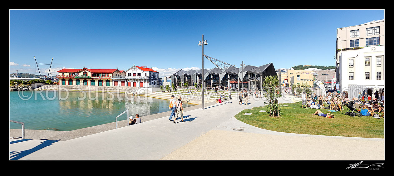 Image of Wellington waterfront city lagoon with historic Rowing and Boating club, Wharewaka, Odlins and St Johns Ambulance buildings, and people enjoying summer. Panorama, Wellington, Wellington City District, Wellington Region, New Zealand (NZ) stock photo image