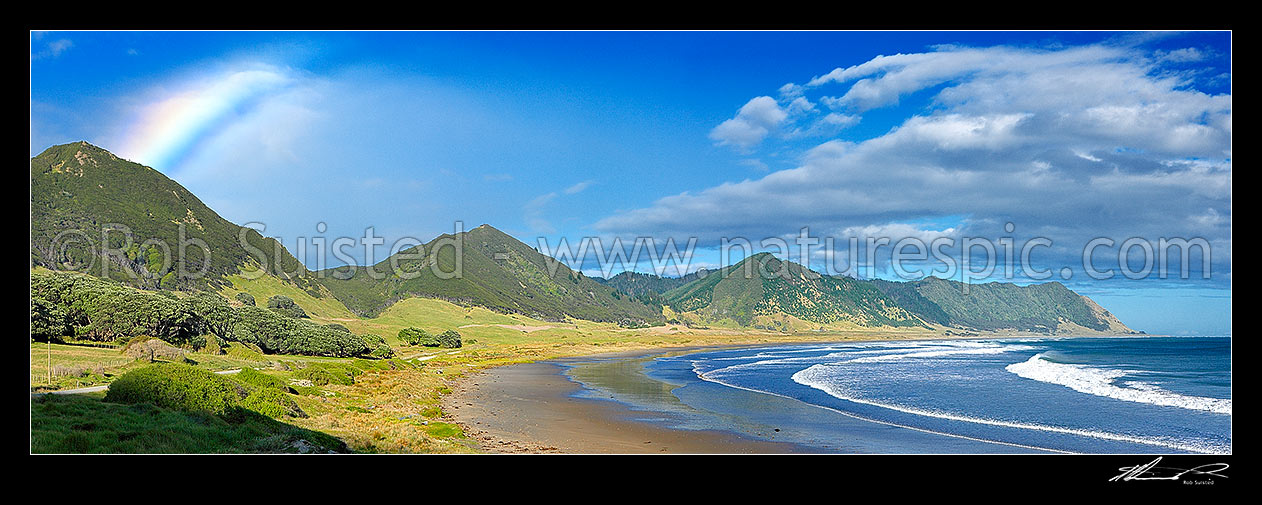 Image of East Cape coastline, with rainbow over Hautai Beach. Kokomukataranga peak left, and Horoera Point right. Panorama, East Cape, Gisborne District, Gisborne Region, New Zealand (NZ) stock photo image