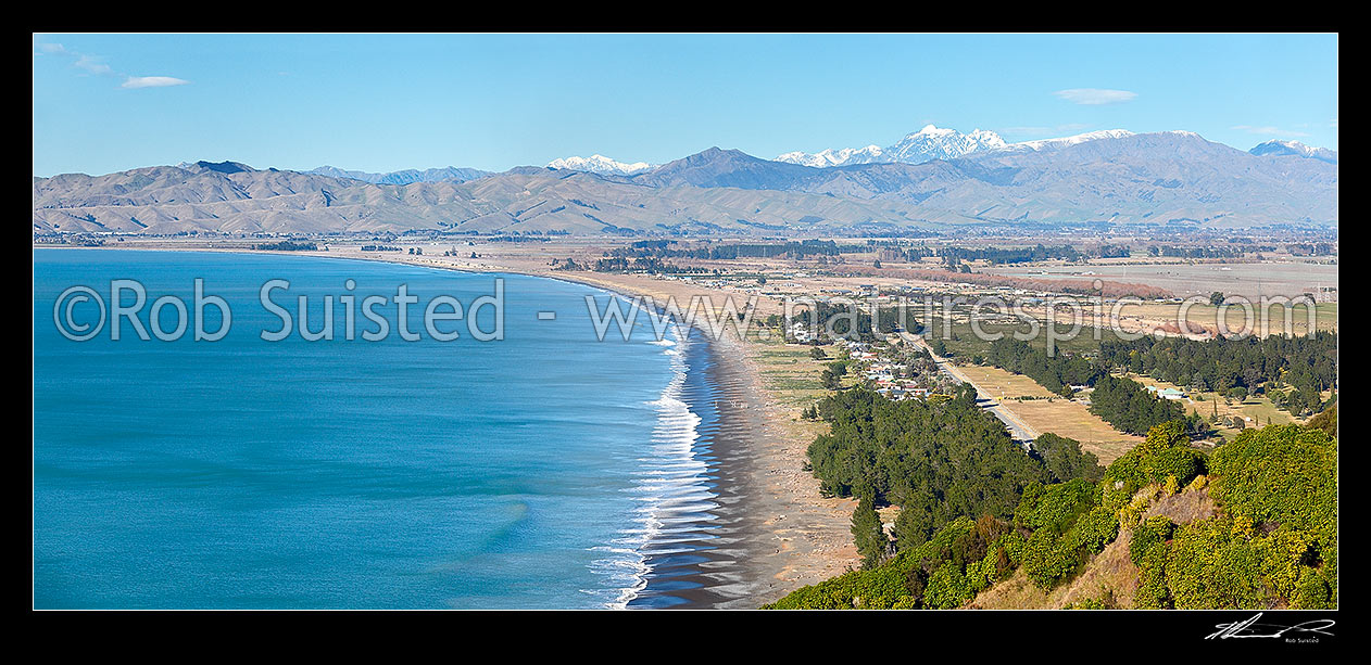 Image of Rarangi Beach with walkers in Cloudy Bay with Wither Hills, Mount Tapuae-o-uenuku (2885m) and Inland Kaikoura Ranges above. Panorama, Rarangi, Marlborough District, Marlborough Region, New Zealand (NZ) stock photo image