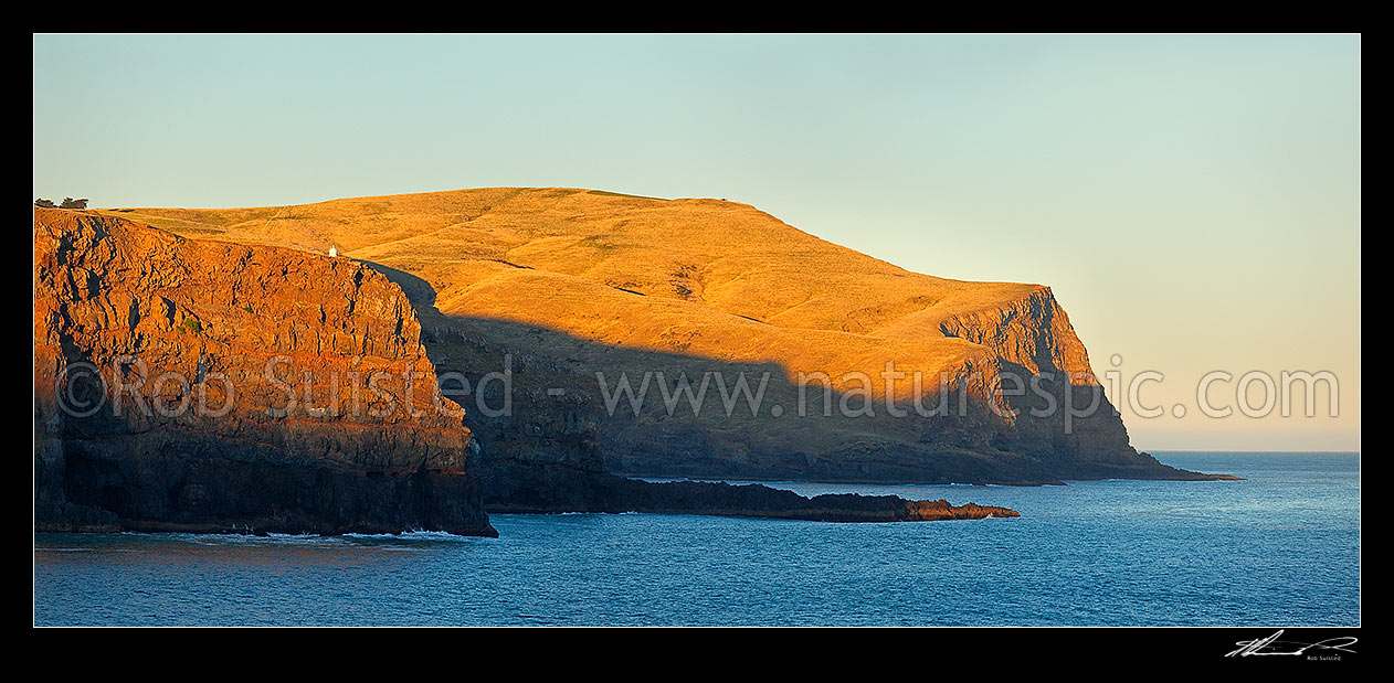 Image of Akaroa Head lighthouse on cliffs above Haylocks Bay, Gateway Point, with Damons Bay centre. Panorama, Banks Peninsula, Christchurch City District, Canterbury Region, New Zealand (NZ) stock photo image