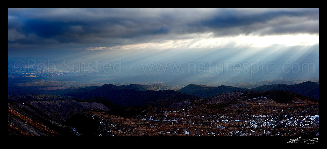 Image of Ohakune (far left), farmland and flanks of Mount Ruapehu being lit by sun shafts behind a passing weather front. Maungaturuturu, Makotuku Rivers. Panorama, Tongariro National Park, Ruapehu District, Manawatu-Wanganui Region, New Zealand (NZ) stock photo image