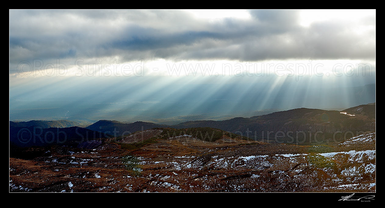 Image of Ohakune (far left), farmland and flanks of Mount Ruapehu being lit by sun shafts behind a passing weather front. Maungaturuturu, Makotuku Rivers and Lake Surprise far right. Panorama, Tongariro National Park, Ruapehu District, Manawatu-Wanganui Region, New Zealand (NZ) stock photo image