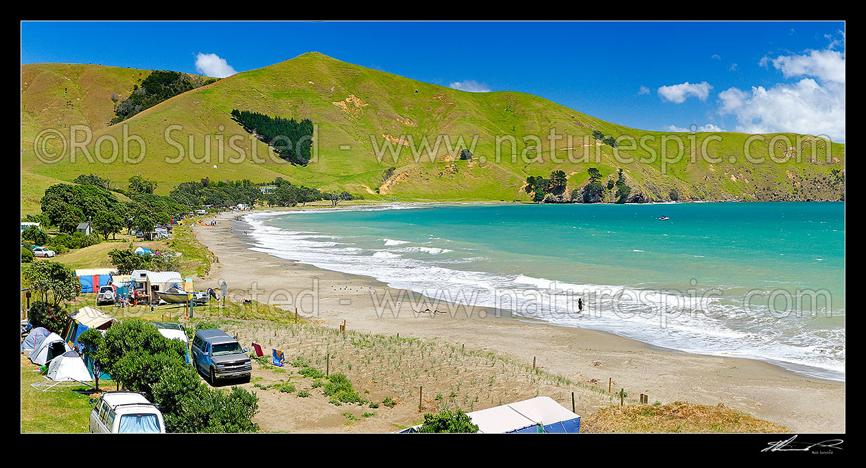 Image of Port Jackson bay beach and Departmenf of Conservation (DOC) campsite with summer campers and tents on foreshore. Panorama, Cape Colville, Thames-Coromandel District, Waikato Region, New Zealand (NZ) stock photo image