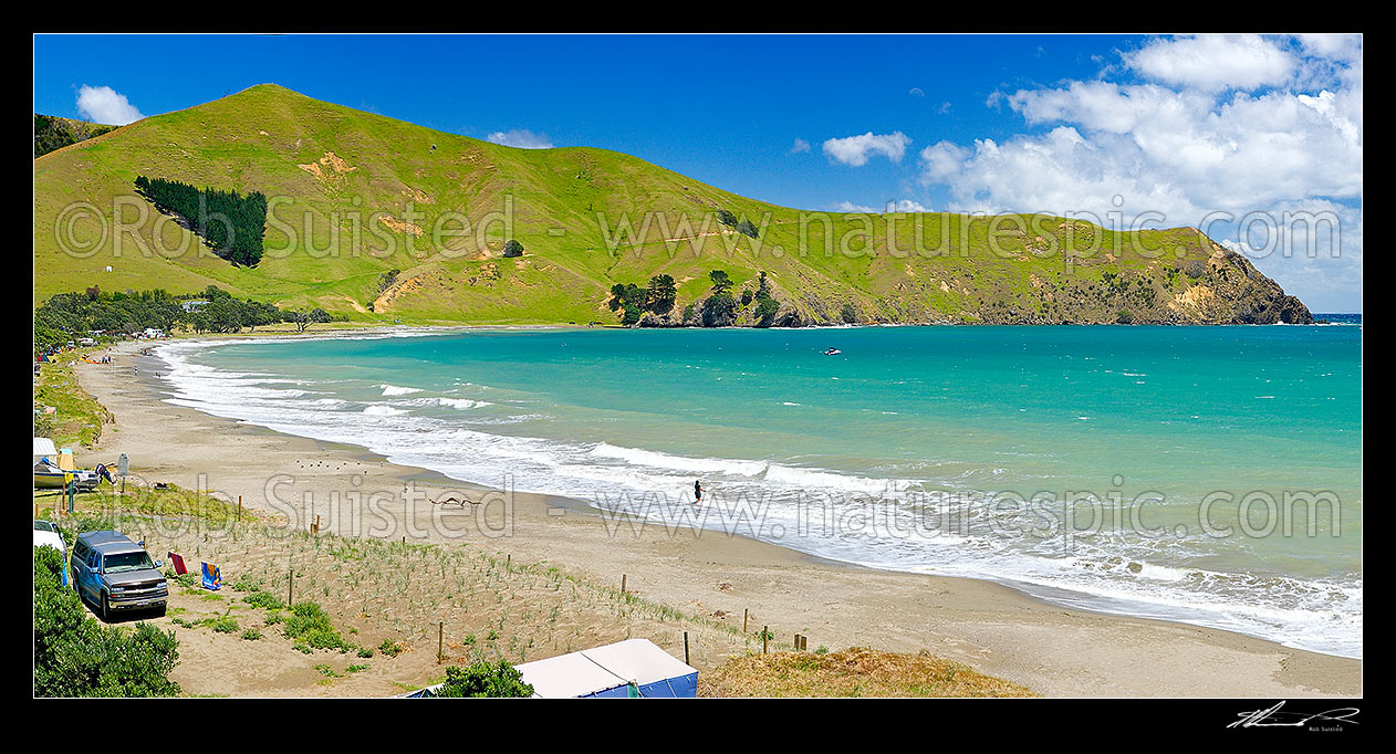 Image of Port Jackson bay beach and Departmenf of Conservation (DOC) campsite with summer campers and tents on foreshore. Kaiiti Point behind. Panorama, Cape Colville, Thames-Coromandel District, Waikato Region, New Zealand (NZ) stock photo image