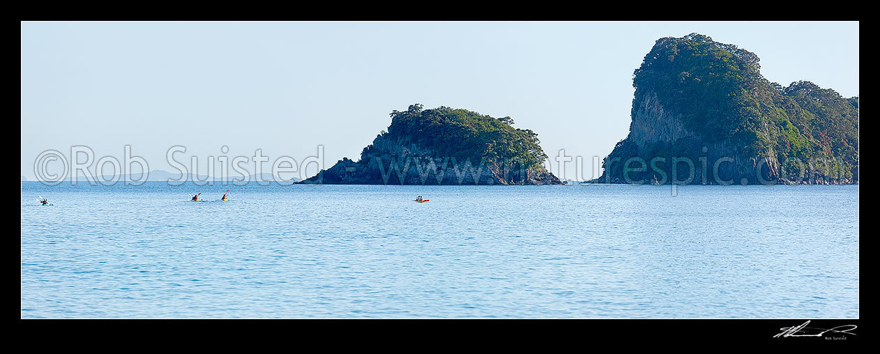 Image of Sea kayakers in Whanganui A Hei Marine Reserve, with Poikeke and Motueka (Pigeon) Islands behind. Cathedral Cove. Panorama, Hahei, Coromandel Peninsula, Thames-Coromandel District, Waikato Region, New Zealand (NZ) stock photo image