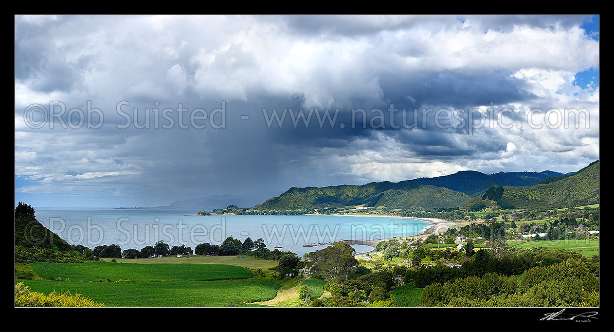 Image of Looking across Omaio Bay, Otuwhare and Omaio township towards Te Kaha Point in distance, with weather rain storm cloud over Okahu Point and coast. Panorama, Te Kaha, East Cape, Opotiki District, Bay of Plenty Region, New Zealand (NZ) stock photo image