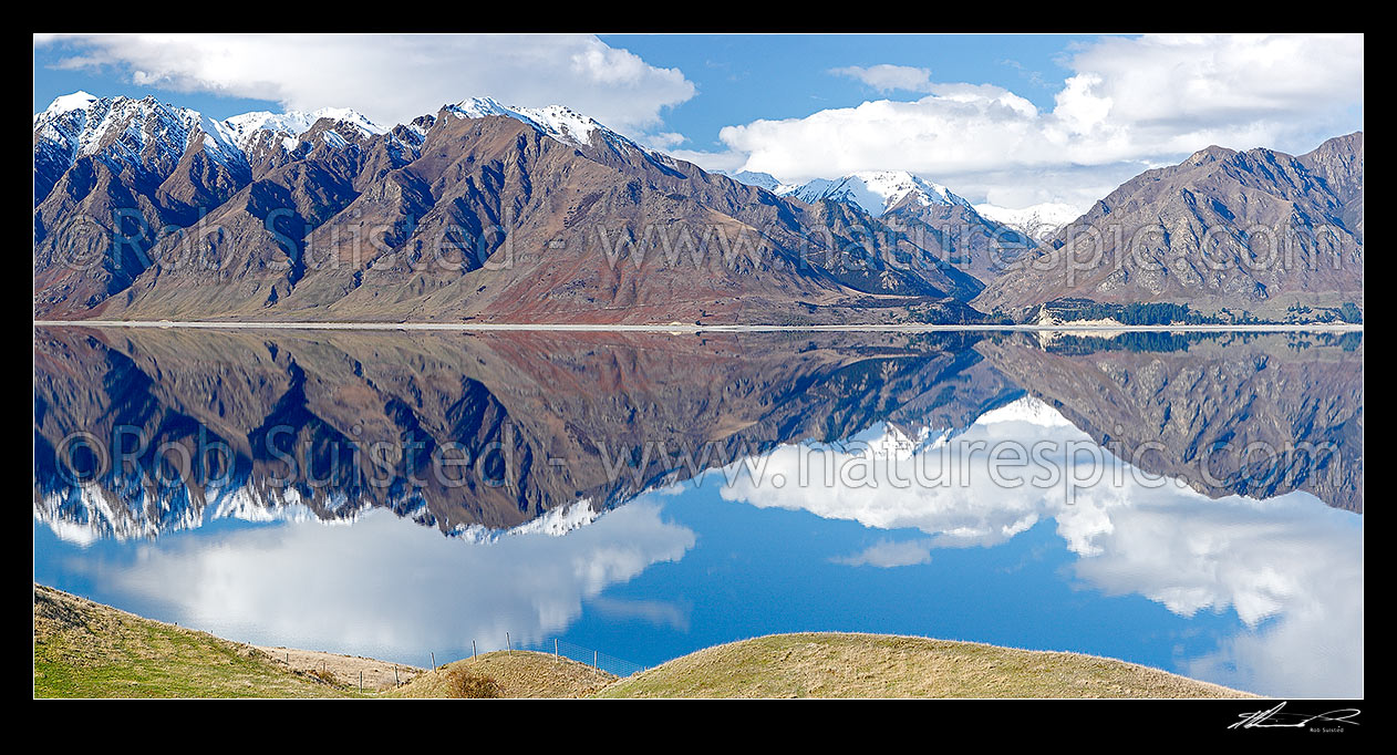 Image of Lake Hawea reflecting surrounding mountains with Timaru River centre right. Panorama, Lake Hawea, Otago, Queenstown Lakes District, Otago Region, New Zealand (NZ) stock photo image