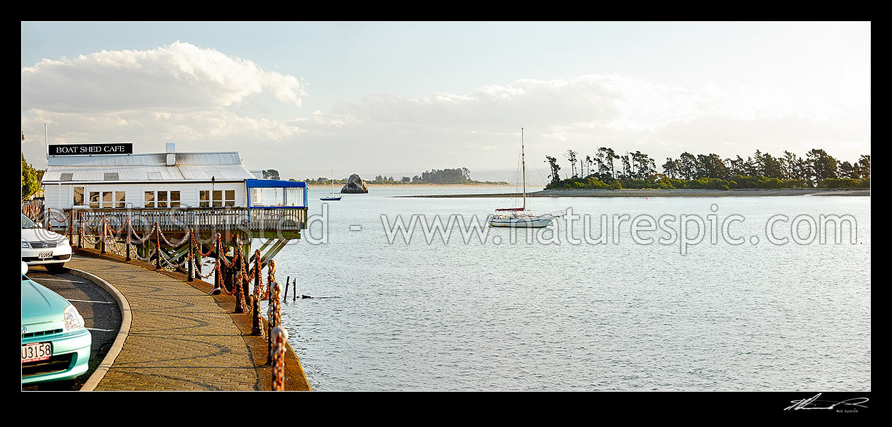 Image of The Boatshed Caf on the Nelson waterfront, with moored yacht in front of Haulashore Island. Panorama, Nelson, Nelson City District, Nelson Region, New Zealand (NZ) stock photo image