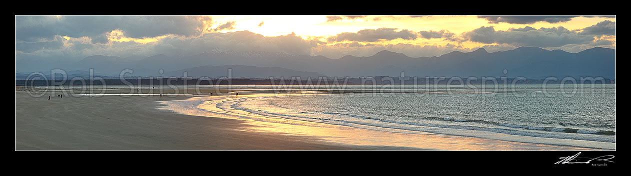 Image of Tahunanui Beach with people enjoying walking in the evening, with Arthur Range and Kahurangi National Park beyond. Panorama, Nelson, Nelson City District, Nelson Region, New Zealand (NZ) stock photo image