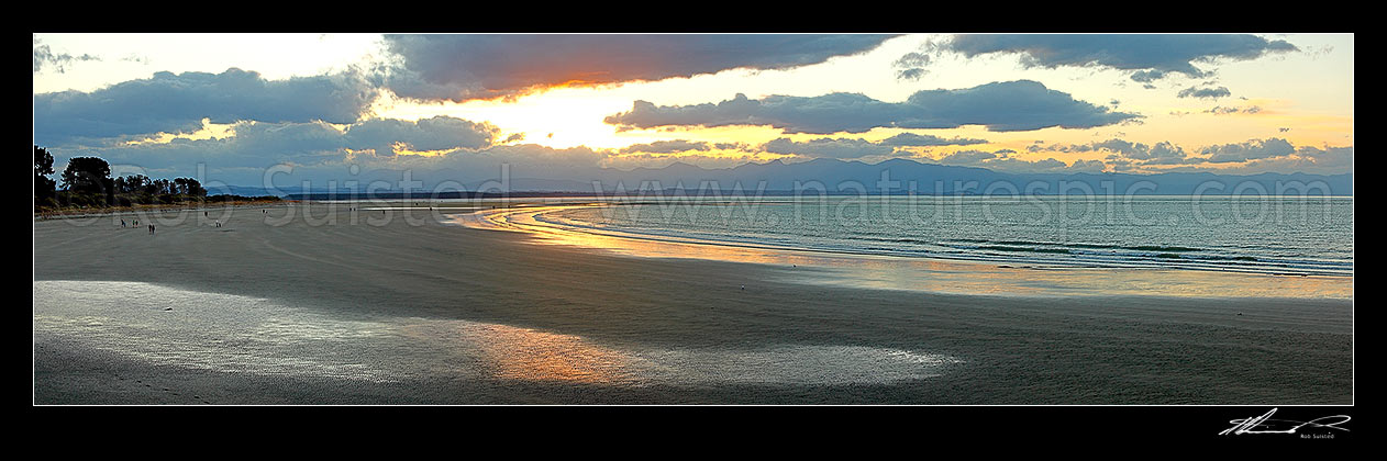 Image of Tahunanui Beach with people enjoying walking in the evening, with Arthur Range and Kahurangi National Park beyond. Panorama, Nelson, Nelson City District, Nelson Region, New Zealand (NZ) stock photo image