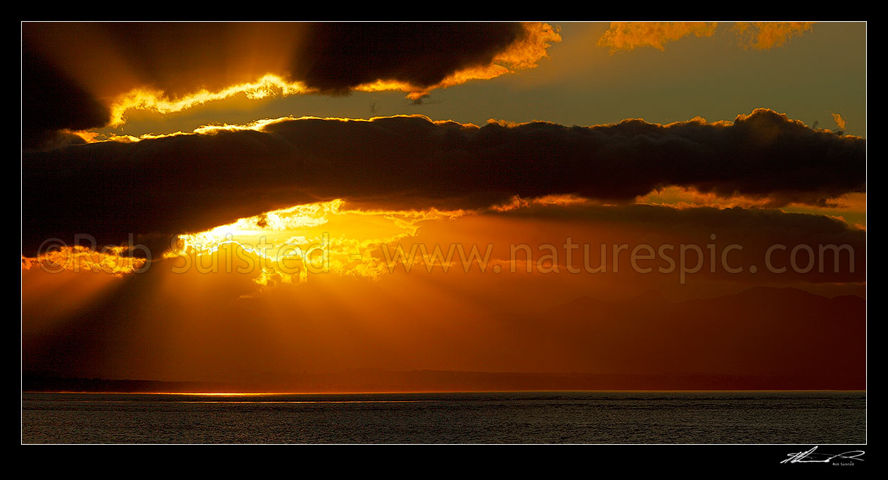 Image of Dramatic sunset, rays of light and clouds over Tasman Bay and Rabbit Island, from Tahunanui Beach, Nelson, Nelson City District, Nelson Region, New Zealand (NZ) stock photo image