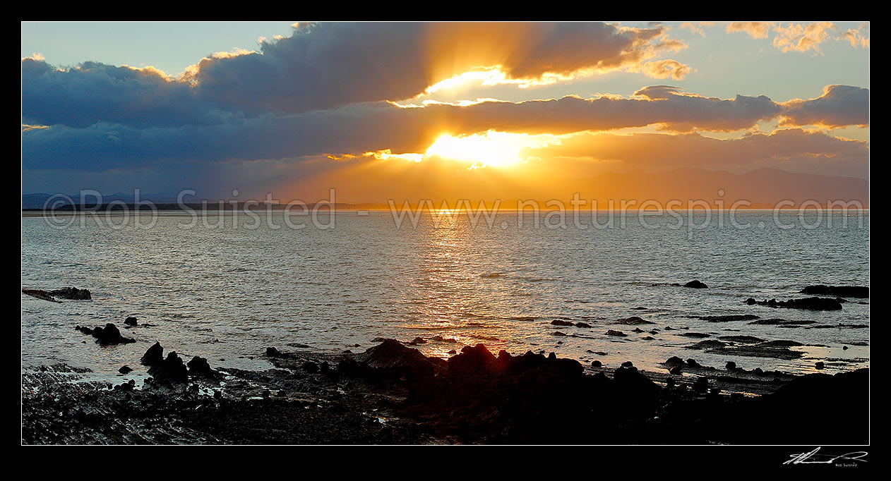 Image of Dramatic sunset, rays of light and clouds over Tasman Bay and Rabbit Island, from Tahunanui Beach. Panorama, Nelson, Nelson City District, Nelson Region, New Zealand (NZ) stock photo image