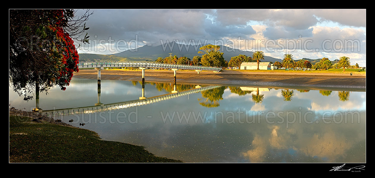 Image of Raglan walking bridge over a harbour inlet to Putoetoe point and campground at dawn. Mt Karioi behind. Panorama, Raglan, Waikato District, Waikato Region, New Zealand (NZ) stock photo image