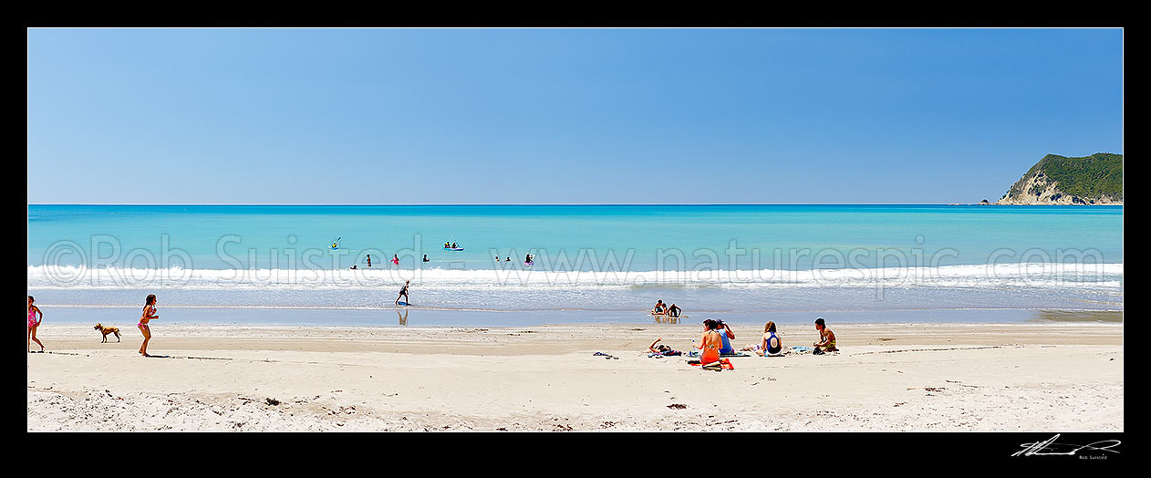 Image of Families enjoying the summer on Waipiro Bay beach with azure blue water. Swimming, digging, sunbathing, kayaking and wave skis in surf. Panorama, Waipiro Bay, East Coast, Gisborne District, Gisborne Region, New Zealand (NZ) stock photo image