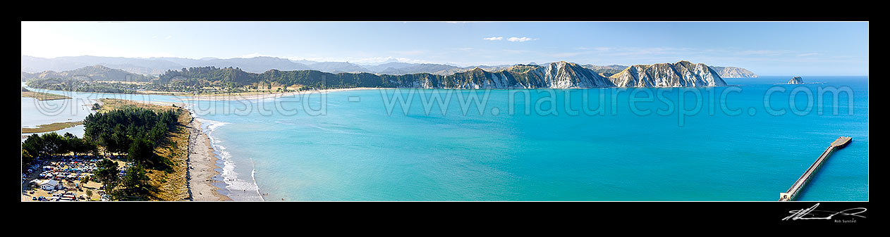 Image of Tolaga Bay from the Uawa River mouth, past to Te Karaka Point (and island) and Marau Point, to the old wharf. Mt Hikurangi (1752m) distant centre. Panorama, Tolaga Bay, Gisborne District, Gisborne Region, New Zealand (NZ) stock photo image