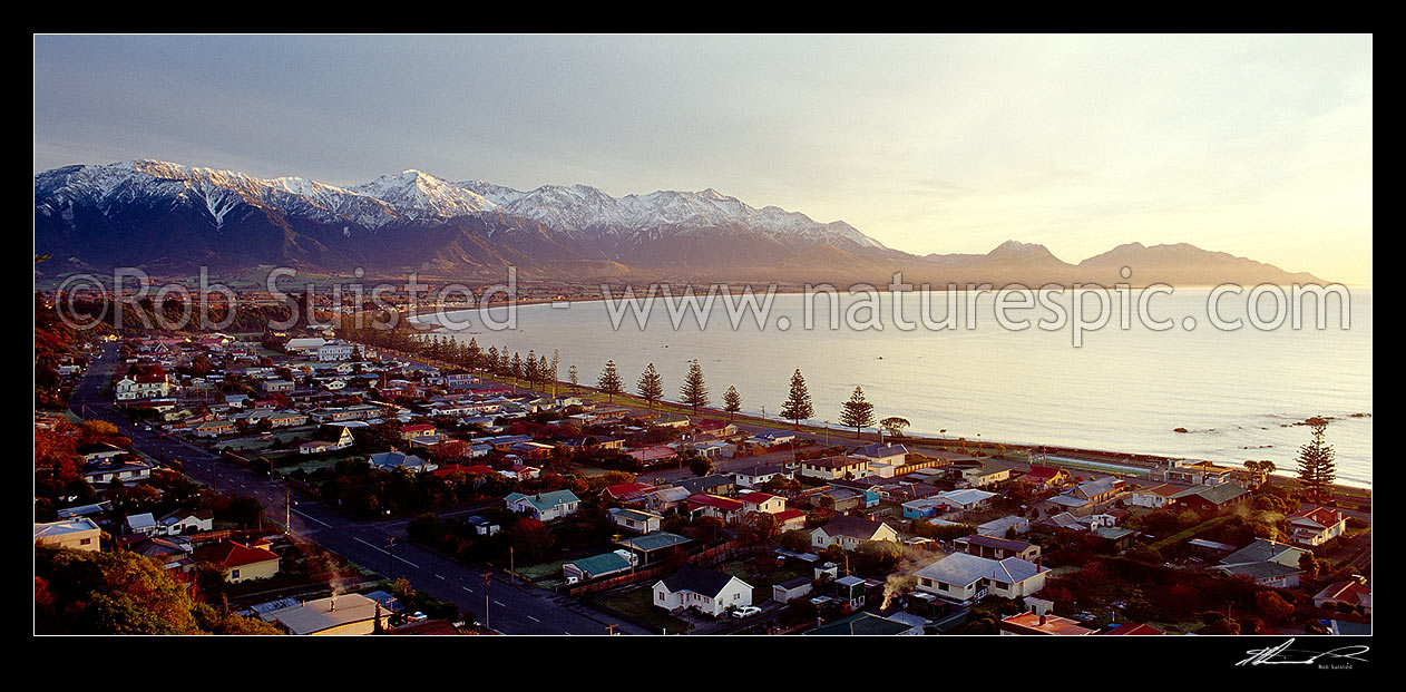 Image of Kaikoura township at dawn. Snow covered Seaward Kaikoura Range and Mt Fyffe beyond. Panorama, Kaikoura, Kaikoura District, Canterbury Region, New Zealand (NZ) stock photo image