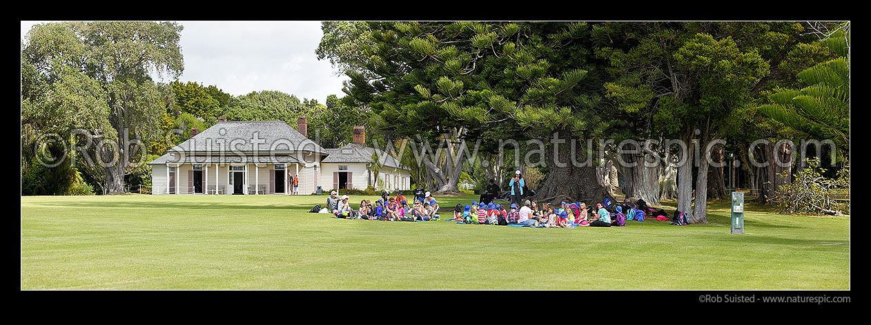 Image of The Treaty House (1834) in the Waitangi Treaty Grounds with visiting school children visiting. Te Tiriti o Waitangi. Panorama, Waitangi, Bay of Islands, Far North District, Northland Region, New Zealand (NZ) stock photo image