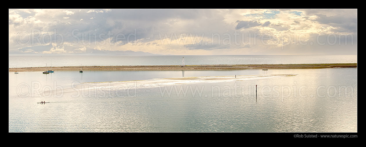 Image of Nelson Haven and Boulder Bank lighthouse, built 1862, with moored sailboats and waka ama paddlers passing. Panorama, Nelson, Nelson City District, Nelson Region, New Zealand (NZ) stock photo image