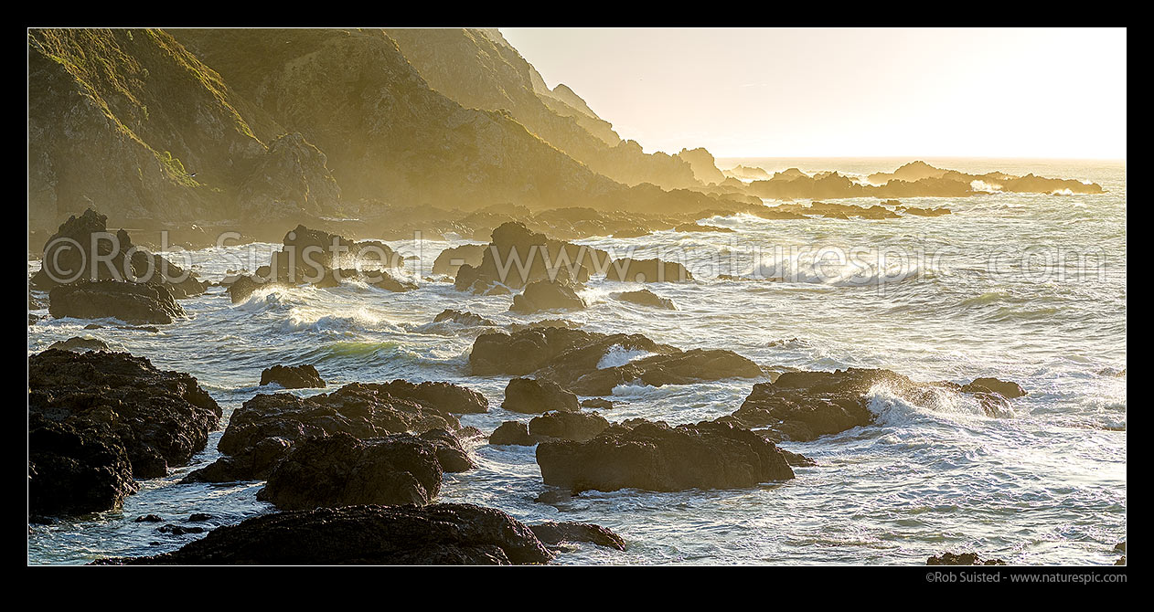 Image of Titahi Bay coastline with waves crashing onto the rocky shore in late afternoon sun. Whitireia Park. Panorama, Titahi Bay, Porirua City District, Wellington Region, New Zealand (NZ) stock photo image