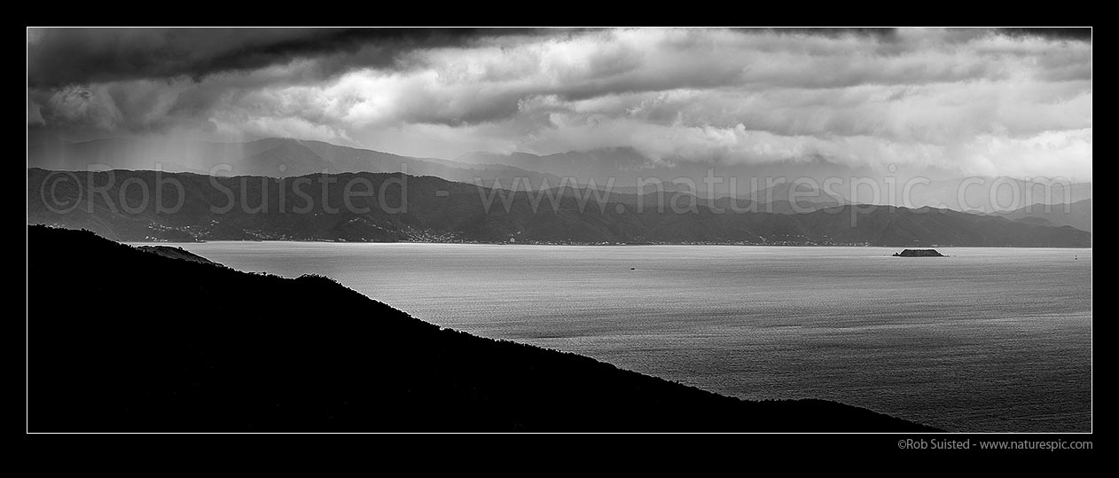 Image of Wellington Harbour with approaching weather. Days Bay and Eastbourne coast, Remutaka (Rimutaka) Ranges behind, Makaro / Ward Island right. Ferry crossing harbour. Black and White panorama, Wellington, Wellington City District, Wellington Region, New Zealand (NZ) stock photo image