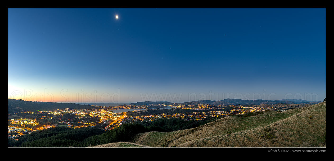 Image of Moonrise over Porirua City and Harbour at twilight. Titahi Bay centre, Cannons Creek, Waitangirua and Porirua East right. Plimmerton, Paremata and Kapiti Island distant. Panorama, Porirua, Porirua City District, Wellington Region, New Zealand (NZ) stock photo image