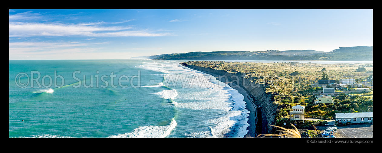 Image of Port Waikato beach in front of surf club, with surfers enjoying waves. Black ironsands beach and dunes with Waikato River mouth beyond, and Whatipu Heads in distance left. Panorama, Port Waikato, Franklin District, Waikato Region, New Zealand (NZ) stock photo image