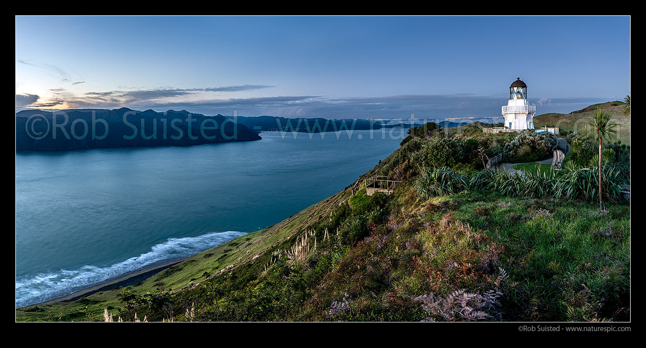 Image of Manukau Harbour Entrance, at dusk, with Awhitu South Head lighthouse high above. Auckland City, Sky Tower and Cornwallis far distance. Twilight panorama, Awhitu Peninsula, Papakura District, Auckland Region, New Zealand (NZ) stock photo image