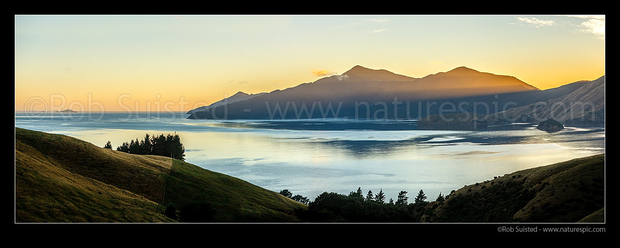 Image of Admiralty Bay sunrise panorama, Marlborough Sounds. Sunshafts over Puketea Bay and Matatoko Point. Trio Islands (Kuru Pongi) far left, French Pass, Marlborough Sounds, Marlborough District, Marlborough Region, New Zealand (NZ) stock photo image