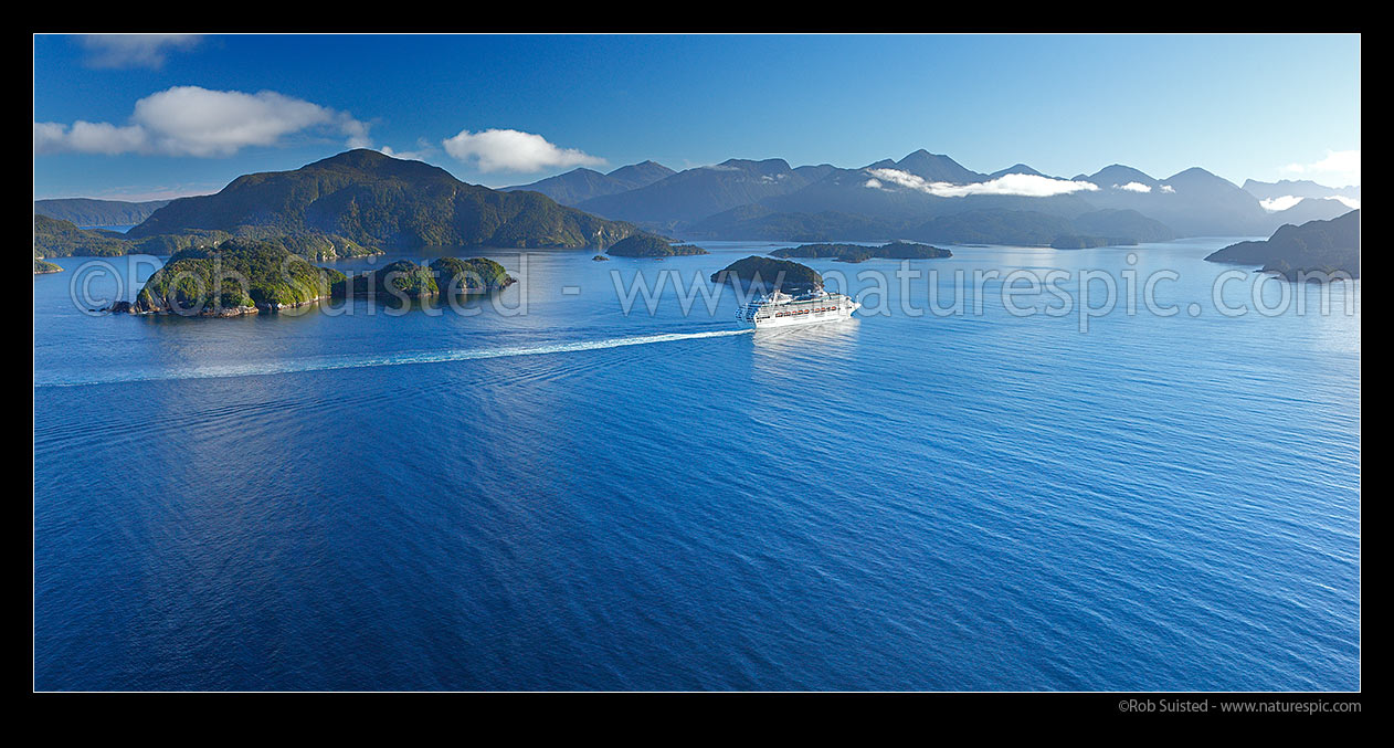 Image of Cruise ship passing through Dusky Sound, heading north on calm morning. Resolution Island behind. Panorama, Fiordland National Park, Southland District, Southland Region, New Zealand (NZ) stock photo image