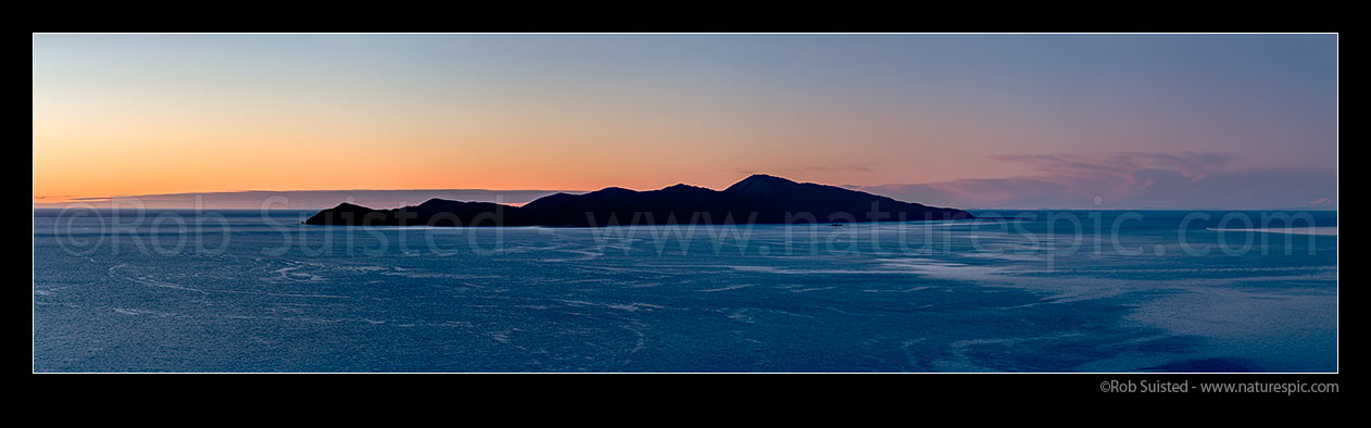 Image of Kapiti Island at twilight, silhouetted against sunset. Mt Taranaki just visible on left end, and Mt Ruapehu far right. Kapiti Island Nature Reserve. Panorama, Paekakariki, Kapiti Coast District, Wellington Region, New Zealand (NZ) stock photo image