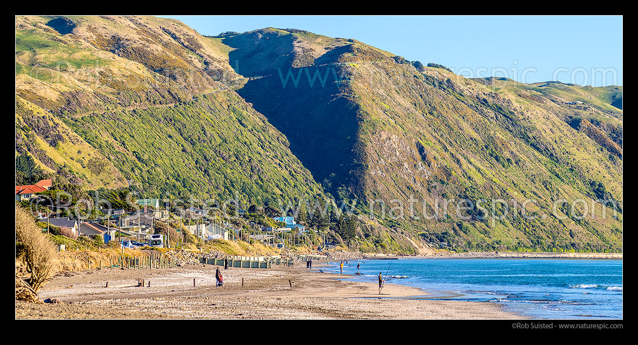 Image of Paekakariki Beach panorama. People fishing and walking on beach, with Paekakariki Hill Road above the small coastal community, Paekakariki, Kapiti Coast District, Wellington Region, New Zealand (NZ) stock photo image