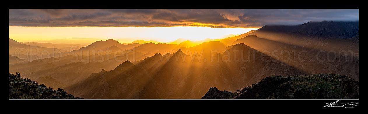 Image of Dramatic sunrise over Awatere Valley (left). Crepuscular rays lighting the Hodder River Valley, Camden and Gladstone Downs Stations. Panorama, Awatere Valley, Marlborough District, Marlborough Region, New Zealand (NZ) stock photo image