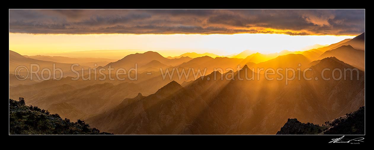 Image of Awatere Valley (left) sunrise, with crepuscular rays of sunlight lighting the Hodder River valley, Gladstone Downs and Camden Stations. Panorama, Awatere Valley, Marlborough District, Marlborough Region, New Zealand (NZ) stock photo image